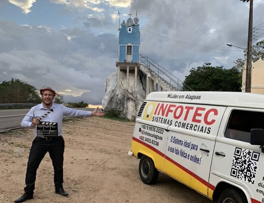 Jorge Regis ao lado da Kombi motor home da expedição, em frente a uma capela no alto de uma pedra